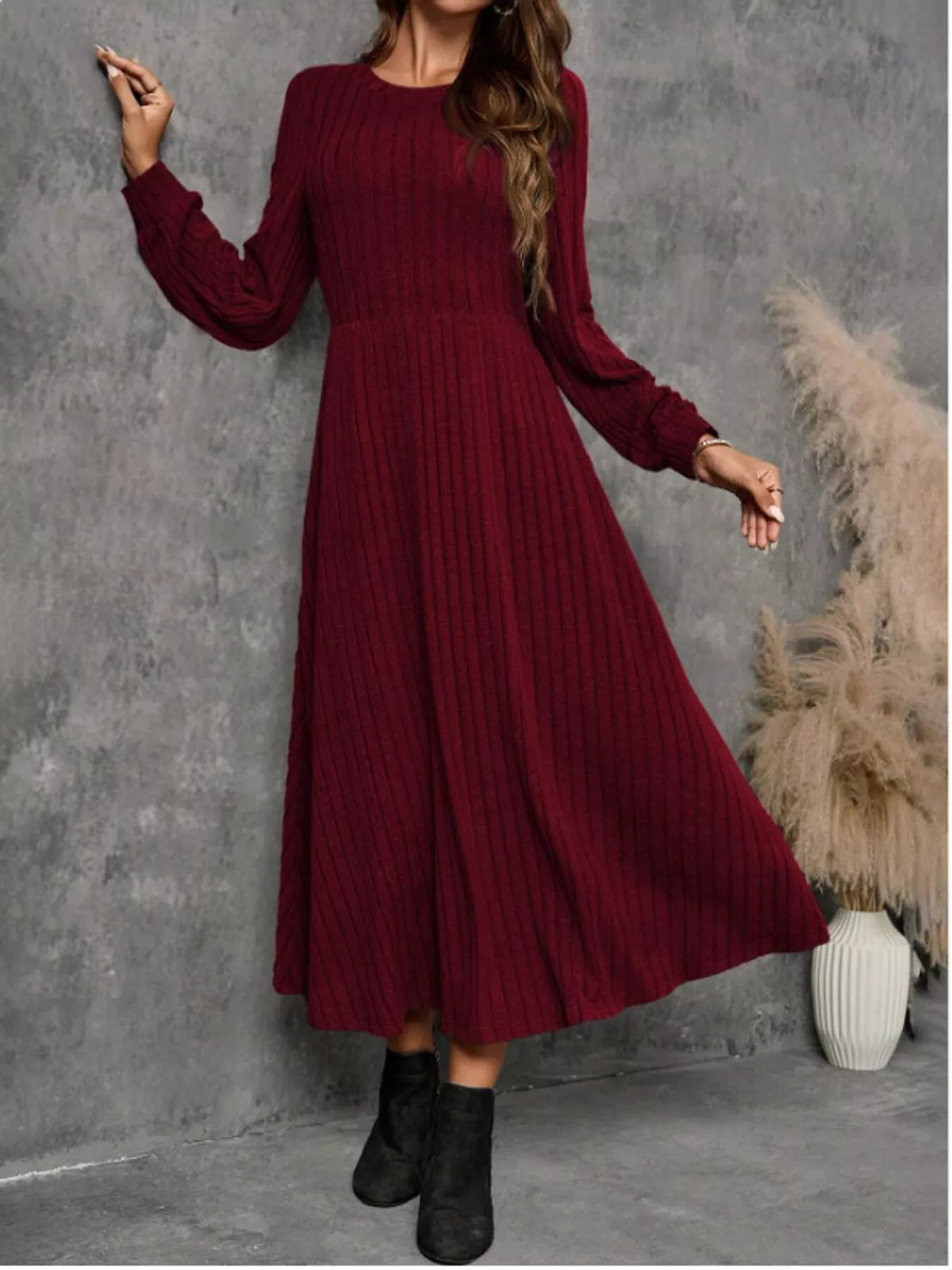 Burgundy ribbed knit long-sleeve A-line midi dress on a model, with the hem swinging to one side.