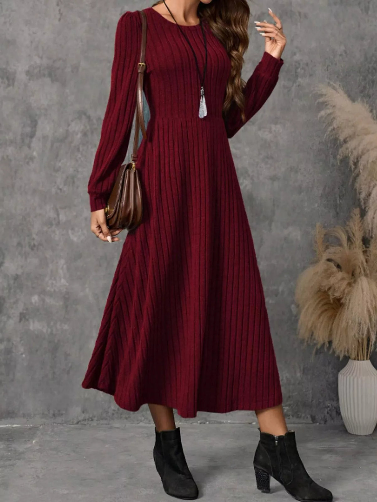 Burgundy ribbed knit A-line midi dress with long sleeves, shown on a model carrying a brown shoulder bag.