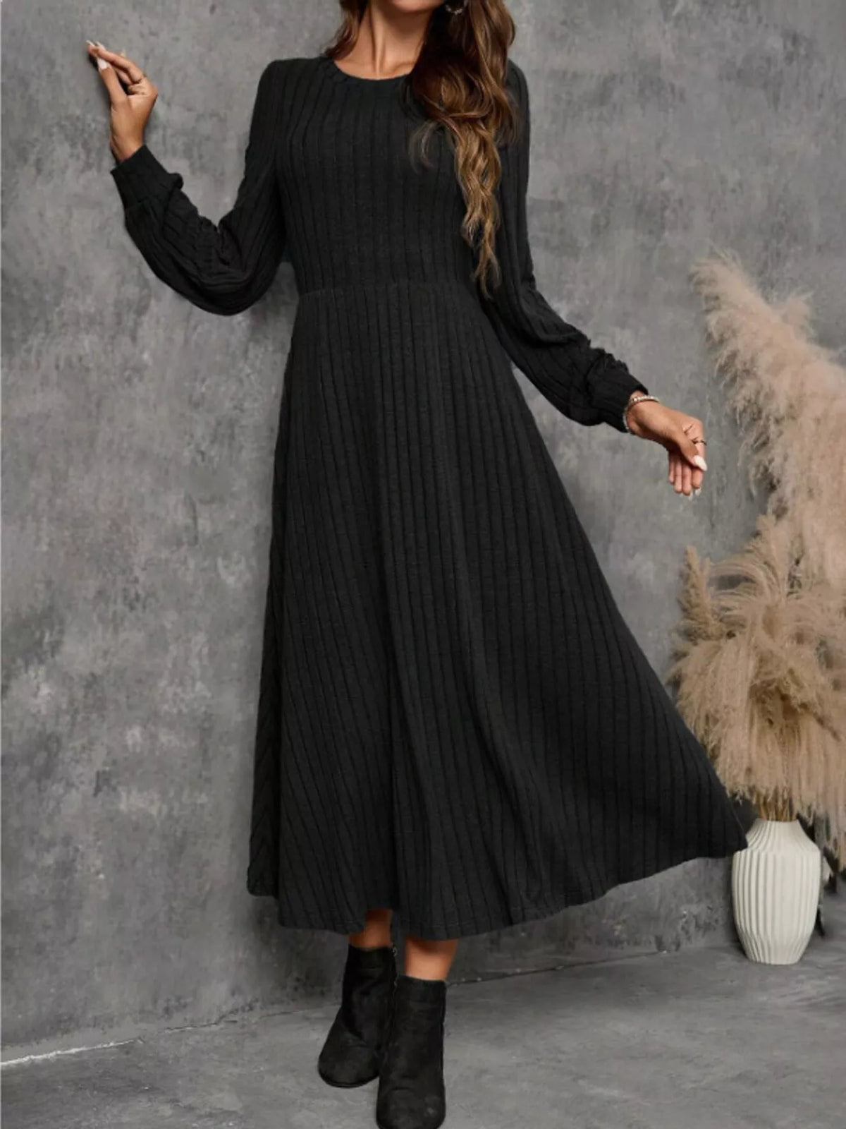 Black ribbed knit long-sleeve A-line midi dress on a model, with the hem swinging to one side.